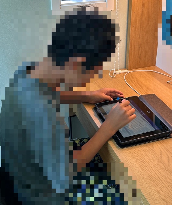 進研ゼミのタブレットを机に平置きして前かがみになっている様子